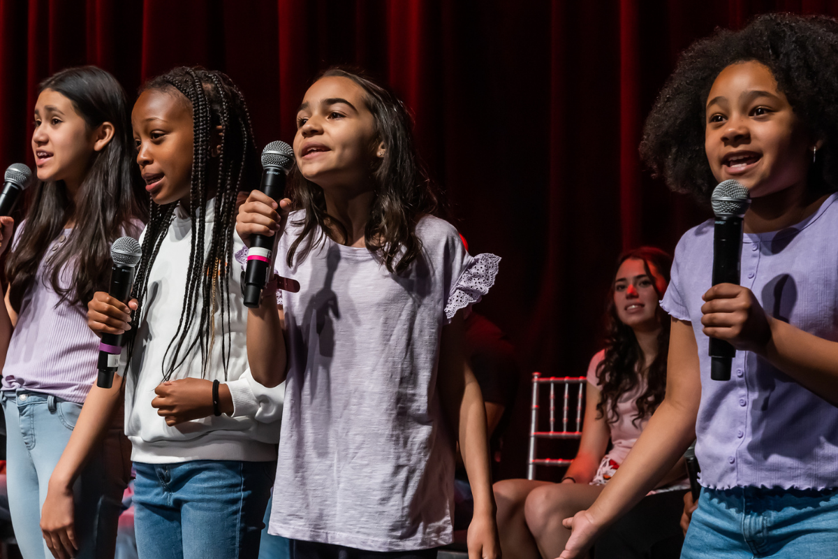 kids performing on a stage with mics